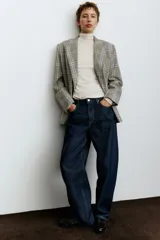 Jean de tiro alto con corte baggy, confeccionado en denim de algodón. Presenta diseño de cinco bolsillos, cierre frontal con botón y silueta de pierna curva con volumen en la cadera.