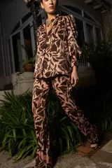 Pantalón de corte recto y tiro medio, confeccionado en tela fluida con estampado botánico en tonos marrón y beige. Presenta cintura elástica para mayor comodidad.