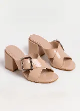Sandalias de cuero vacuno charolado color beige, con taco ancho, tiras cruzadas y hebilla metálica decorativa.