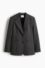 Blazer de mujer gris oscuro con estampado Príncipe de Gales (a cuadros). Presenta solapas de muesca, cierre frontal de dos botones, hombreras y bolsillos delanteros con solapa.