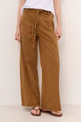 Jean tostado de corte wide leg, tiro medio con presillas y lazo ajustable en la cintura. Presenta bolsillos delanteros y traseros, costuras decorativas verticales y terminación desmechada en el ruedo.