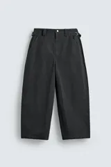 Pantalón de corte relajado confeccionado en tejido de algodón. Presenta cintura con trabillas laterales ajustables, bolsillos frontales y traseros, y un diseño distintivo de costuras laterales giradas que recorren la pernera.
