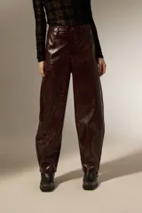 Pantalon de eco-cuero con diseño barrel, de tiro alto y corte holgado. Cuenta con bolsillos laterales y cierre frontal con botón.