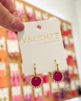 Aros colgantes con aro de acero dorado y dije circular fucsia con borde de strass.