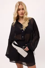 Vestido corto de chiffon color verde lima, con transparencia, cuello camisero, botones frontales y elástico en la cintura. Las mangas son largas y abullonadas con puños elásticos.