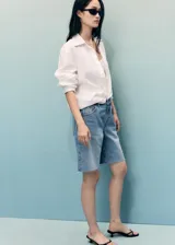 Short de denim tiro medio con diseño de cinco bolsillos, trabillas para cinto y bajo deshilachado.