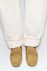 Mocasín de serraje color tostado, con copete subido, antifaz en la parte delantera y detalle fruncido en la parte trasera con tirador y aplique metálico.