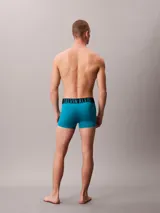 Pack de tres bóxers tipo trunk Calvin Klein, confeccionados en una mezcla de poliéster reciclado y elastano. Presentan una cinturilla elástica distintiva con el logo de la marca y un diseño de pierna corta para mayor comodidad y ajuste.