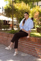 Zapato de cuero color beige, con punta fina, tira sobre el empeine y pulsera con hebilla al tobillo. Tiene talón descubierto y taco cuadrado.