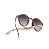 Lentes de sol Indie modelo Hill con montura redonda de madera clara y marrón, y lentes marrones degradados.