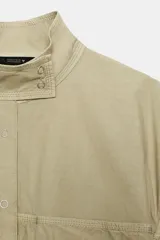 Cazadora de cuello subido con cierre frontal de botones a presión. Presenta mangas largas con detalle de frunces y puños elásticos, además de bajo elástico y bolsillos frontales.