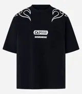 Remera negra de manga corta con cuello redondo, corte oversized y detalles de diseño en los hombros que simulan llamas en blanco. En el centro del pecho lleva un estampado rectangular con el texto "RACE TEAM" y debajo la palabra "OVERDRIVE".