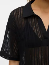 Remera negra oversize con cuello tipo polo y mangas cortas con hombros caídos. Confeccionada en punto single jersey con mezcla de algodón, algodón reciclado y poliéster reciclado. Silueta amplia y relajada.