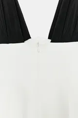 Vestido corto bicolor con cuerpo blanco y tirantes anchos negros plisados en contraste, de escote en pico y corte ajustado.