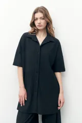 Vestido camisero negro con textura plisada, corte midi y cierre frontal con botones.