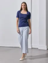 Buzo azul de tejido acanalado, con escote cuadrado y aplique de botones.