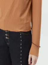 Polera de manga larga confeccionada en tela rib color bordó, con cuello alto y hombreras. Presenta costuras a la vista con pespuntes en hilo de color contrastante en el cuello, puños, hombros y ruedo.