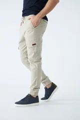 Pantalón cargo color verde oliva, de corte slim, con cintura elastizada y cordón ajustable. Presenta bolsillos laterales tipo cargo con botones y puños elásticos en los tobillos.