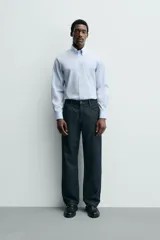 Camisa de corte slim fit confeccionada en tejido de algodón, color celeste. Cuenta con cuello abotonado, manga larga con puños ajustables mediante botón y cierre frontal con botonadura.