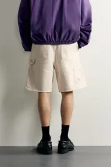 Bermuda relaxed fit color marrón con efecto lavado, cinco bolsillos, bolsillos frontales de carpintero y cierre frontal con cremallera y botón.