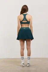 Pollera deportiva corta color verde inglés, con calza incorporada que incluye bolsillo invertido para pelotas. Posee cintura ancha de tiro alto y tejido elastizado de secado rápido.
