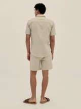 Conjunto de camisa de manga corta con cuello solapa y short con cordón ajustable, ambos en tejido ligero a rayas verticales celestes y blancas.