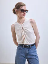 Musculosa color crudo con escote redondo y lazos ajustables en el centro.