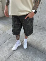 Bermuda tipo cargo con corte baggy, diseño de camuflaje en tonos verdes y negros, con bolsillos laterales y cierre frontal.