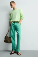 Jeans de mezclilla de corte recto, tiro medio, color verde vibrante con efecto lavado. Presenta cierre frontal con cremallera y botón, y cinco bolsillos.