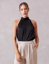 Blusa de satén color negro con diseño plisado, cuello alto tipo halter y corte sin mangas.