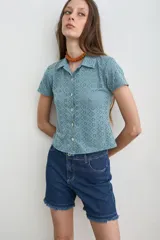 Camisa de broderie color celeste, con cuello camisero, manga corta y cierre frontal con botones de nácar.