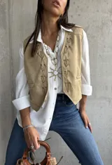 Chaleco beige de gamuza con detalles de nudos decorativos en el frente.
