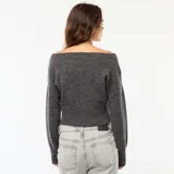 Sweater de punto gris oscuro, con escote Bardot (hombros descubiertos), manga larga y puño y ruedo acanalados. El calce es corto y holgado.