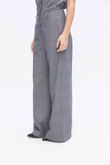 Pantalón de pierna amplia y tiro alto, confeccionado en tejido a rayas con una mezcla de algodón, poliéster y lino. Presenta un diseño de corte sastrero con bolsillos laterales y trabillas para cinturón.