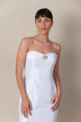 Vestido blanco de tafeta, strapless, con detalle de broche bordado en el escote. Presenta cinta trenzada en la espalda para ajustar y mangas caídas removibles. Vestido con cola.