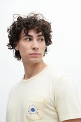 Remera de manga corta color verde agua con bolsillo en el pecho y estampado de un sol.