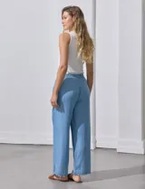 Pantalón celeste de lyocell, corte ancho, con pretina elastizada con lazo de ajuste, bolsillos verticales y ruedo desflecado.