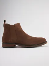 Bota Chelsea de gamuza gris con elásticos laterales, suela de goma marrón y tirador trasero.