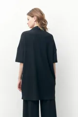 Vestido camisero negro con textura plisada, corte midi y cierre frontal con botones.