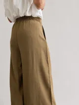 Pantalón palazzo de tiro alto color marrón, confeccionado en lyocell, con cintura elastizada, pinzas delanteras y lazo ajustable.