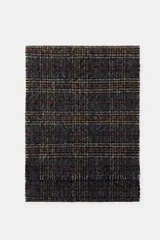 Pañuelo rectangular de lana con diseño de cuadros en tonos gris, marrón y beige, con terminaciones deshilachadas en los extremos.