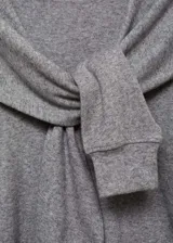 Buzo de punto fino color gris melange, con cuello redondo y diseño de mangas con solapas decorativas superpuestas. Presenta un corte recto y mangas largas con puños ajustados.