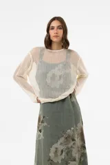 Sweater beige de punto abierto y liviano, con escote redondo, mangas largas y silueta amplia. Presenta detalle de broderie en el ruedo.