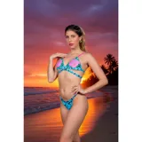 Conjunto de bikini de dos piezas con estampado de camuflaje en tonos celestes y rosas. El top es de estilo triángulo con tiras cruzadas en la parte inferior y breteles en color rosa. La bombacha es de corte tanga.