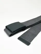 Cinturón de sarga marca Rusty, color negro, con hebilla metálica rectangular y puntera metálica grabada con el logo de la marca.