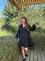 Vestido amplio de lino color verde lima, con cuello mao y abertura frontal con botones de coco. Presenta un diseño con canesú fruncido y volados en los puños de las mangas largas.