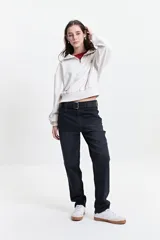 Buzo de felpa color crudo con cuello alto, cierre metálico y bordado de un corazón con rayos en el pecho.