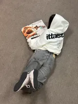 Hoodie de color blanco con capucha, diseño de corte holgado y estampado gráfico en la espalda con tipografía negra.