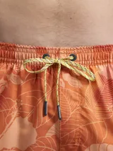 Short de baño con estampado botánico en tonos naranja y coral, con cintura elástica ajustable mediante cordón y malla interior para mayor soporte.