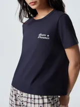 Pijama compuesto por una remera de manga corta color celeste con estampa frontal y un pantalón largo de corte recto con estampado de rayas verticales en tonos neutros.